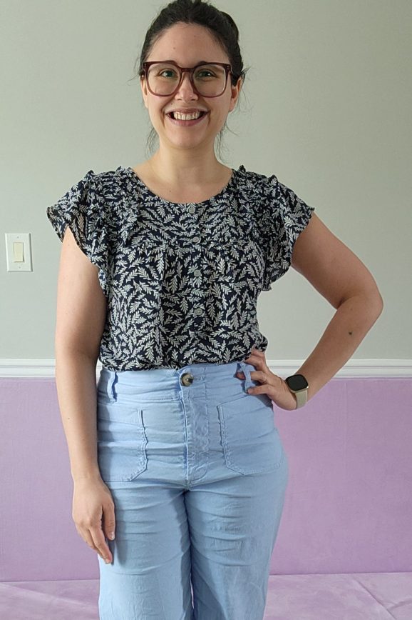 Photo of a woman wearing a dark navy top with ivy print and light blue pants
