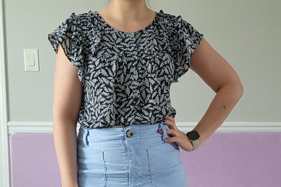 Photo of a woman wearing a dark navy top with ivy print and light blue pants