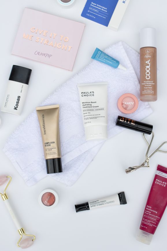 A flat lay photo showing makeup and skincare items on a white background